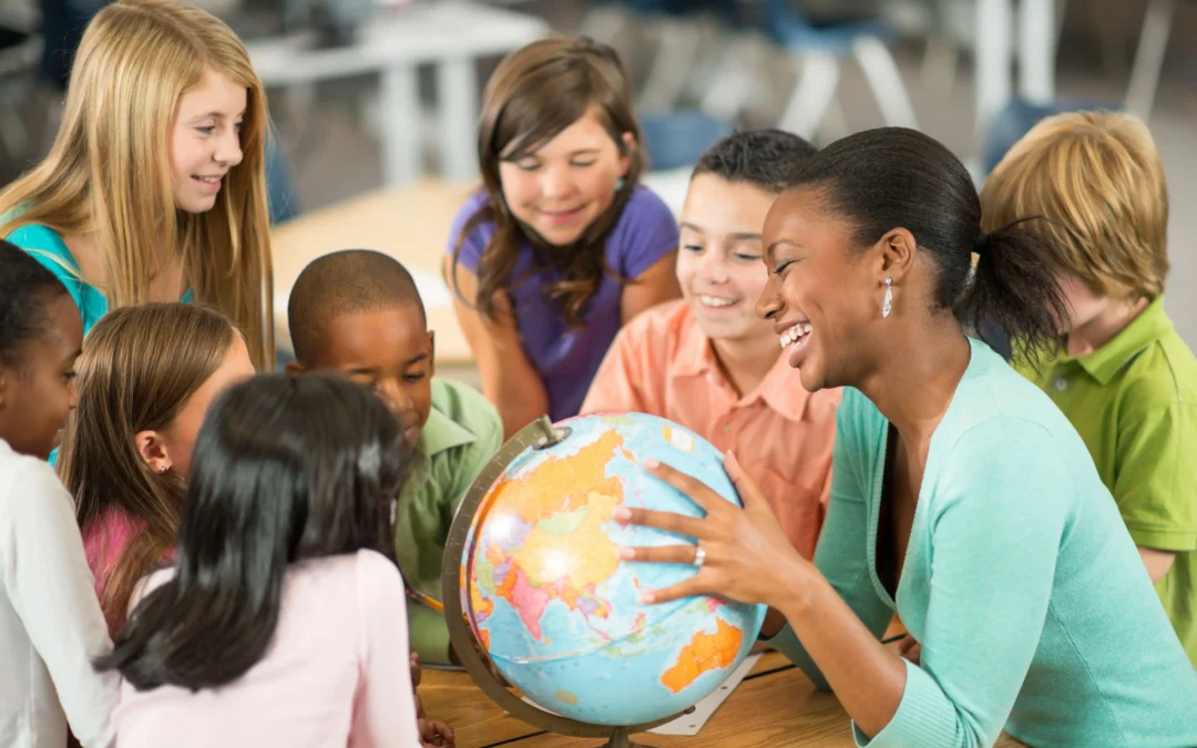Teacher and students gathered around a globe, smiling during a geography lesson in a classroom